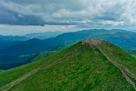Aerial view of the mountain top with many young hikers against the backdrop of a mountain landscape...
