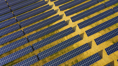 Aerial view of a solar panel farm with rows of panels drawing energy from the sun on a sunny day. Rows of solar panels installed on a vast field.の写真素材
