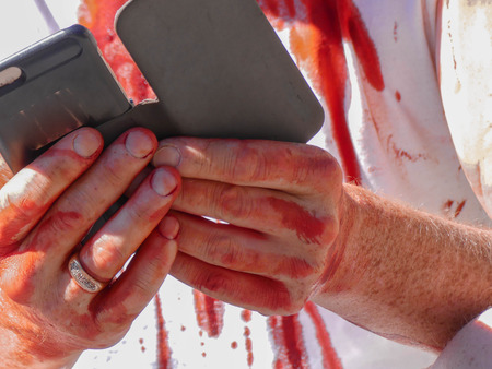 Fake blood wounded person using smartphone haloweenの写真素材