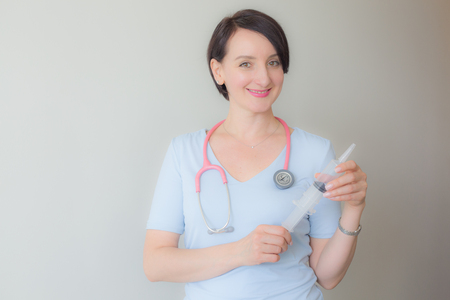 Attractive friendly female doctor holding syringe portraitの写真素材