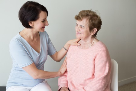 Young female holding hand on shoulder of elderly womanの写真素材