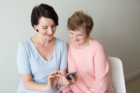 Young woman showing  elderly female how to use smartphoneの写真素材