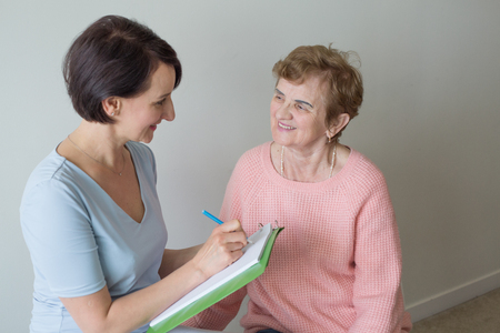 Young and elderly female writing clipboard paperの写真素材