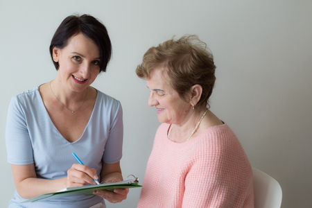 Young woman hand writing elderly female client surveyの写真素材