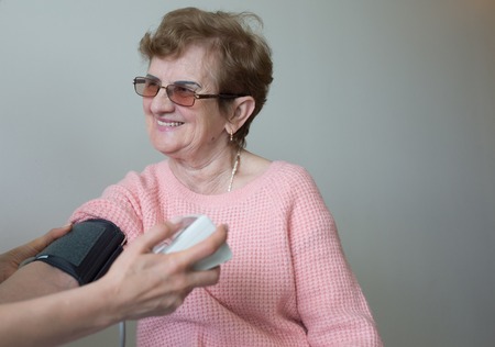 Female doctor checking blood pressure elderly womanの写真素材