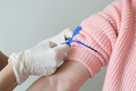 Caregiver hands sterile gloves putting tourniquet armの写真素材