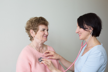 Happy doctor with elderly woman patient stethoscope medical examの写真素材