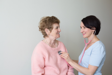 Smiling doctor with elderly woman patient stethoscope medical examの写真素材