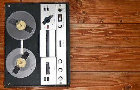 Vintage reel to reel tape recorder on a brown wooden background. Retro tape recorder from the Soviet...