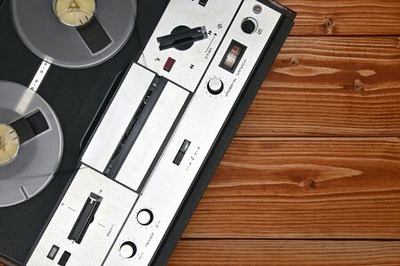 Vintage reel to reel tape recorder on a brown wooden background. Retro tape recorder from the Soviet...