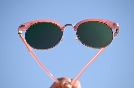 Elegant pink sunglasses on summer beach sandの写真素材