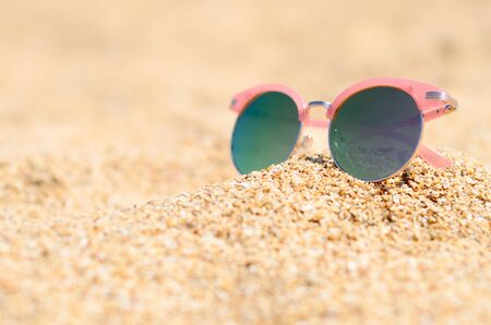Elegant pink sunglasses on summer beach sandの写真素材