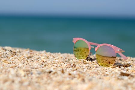 Elegant pink sunglasses on summer beach sandの写真素材