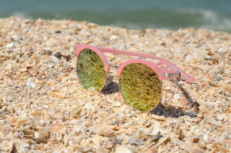 Elegant pink sunglasses on summer beach sandの写真素材