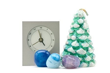 Christmas composition from a wax tree, a clock and azure stones on an isolated white background