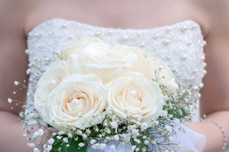 Bouquet of white wedding roses with pearls on the hands of the bride
の写真素材