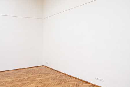 Corner of a large white wall with wooden floor tilesの写真素材