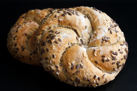 Whole wheat kaiser rolls with sesame seeds on black surface.の写真素材