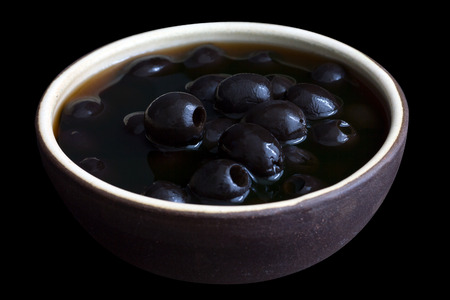 Ceramic rustic bowl of black olives on black surface.の写真素材