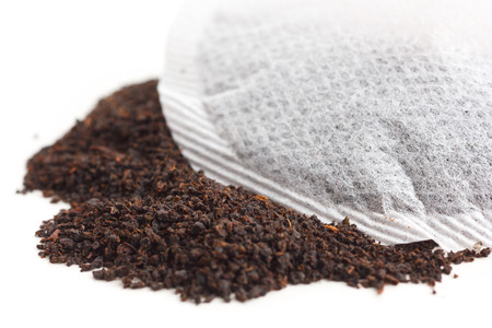 Round teabag on tea leaves on white surface.の写真素材