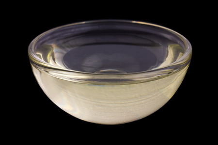 Vegetable oil in small glass dish. Black background.の写真素材