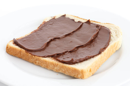 Chocolate nut spread on sliced white bread on plate.