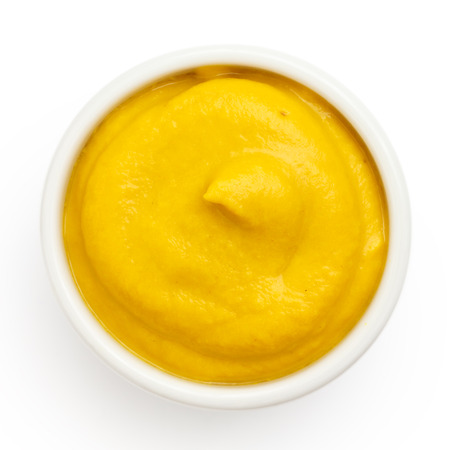 Typical american smooth yellow mustard in round dish from above on white.の写真素材