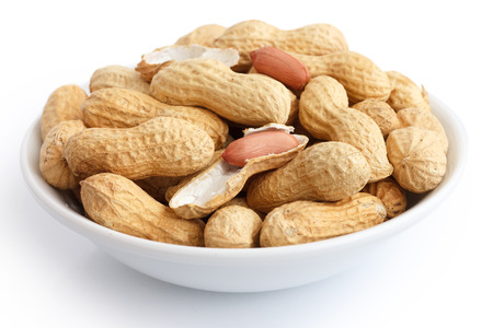 Round ceramic bowl of peanuts in shells. In perspective.