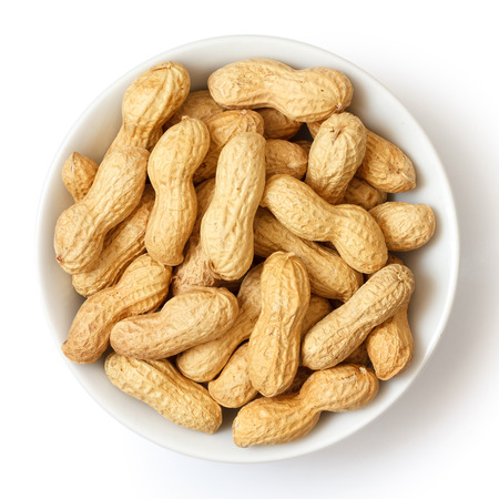 Round ceramic bowl of peanuts in shells. From above.