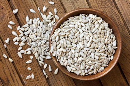 Shelled sunflower seeds in wood bowl isolated from above on rustic table.の写真素材