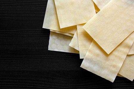 Dry lasagna pasta sheets on black textured wood from above. Space for text.の写真素材