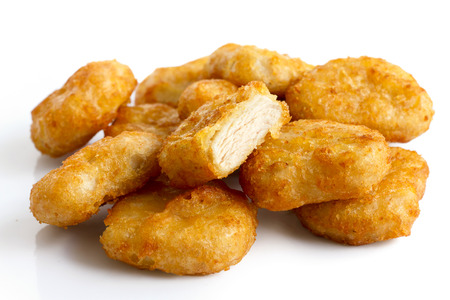 Pile of golden deep-fried battered chicken nuggets isolated on white. One cut with meat showing.の写真素材