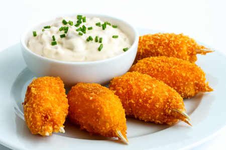 Plate of fried breaded surimi crab claws with bowl of tartar sauce isolated on white.の写真素材
