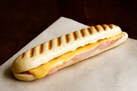 Whole cheese and ham toasted panini melt. On brown paper and wood.の写真素材