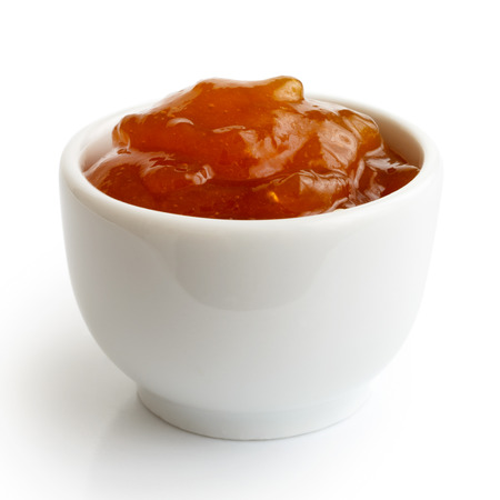 Small ramekin of orange apricot jam isolated on white. In perspective.の写真素材
