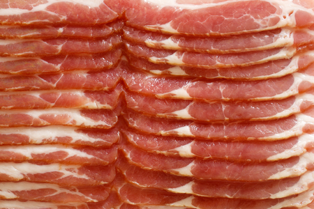 Detail of strips of streaky uncooked bacon isolated on white from above.の写真素材