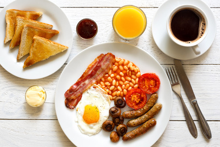 Traditional fried English breakfast with orange juice and coffee from above.の写真素材