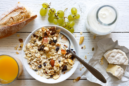 Healthy breakfast with muesli, grapes, cheese and juice on rustic white table from above.の写真素材