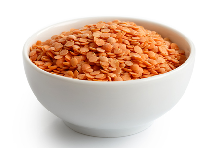 Dry red lentils in white ceramic bowl isolated on white.の写真素材