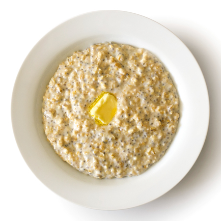 White bowl of oats porridge with chia seeds and butter isolated on white from above.の写真素材