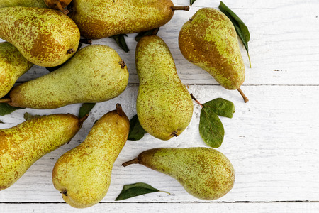 Abate fetel pears with leaves on white painted wood from above. Space for text.