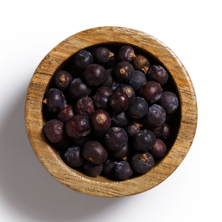 Dry juniper berries in dark wood bowl isolated on white from above.の写真素材
