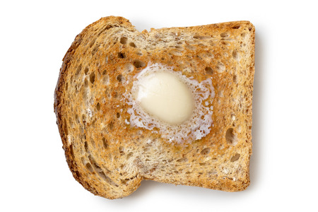 A single slice of whole wheat toast with a knob of melting butter isolated on white from above.の写真素材