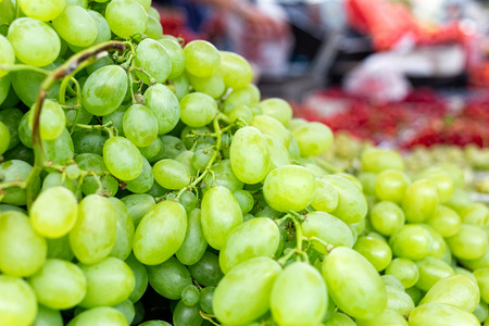 A heap of green grapes at market. Blurry market background.の写真素材