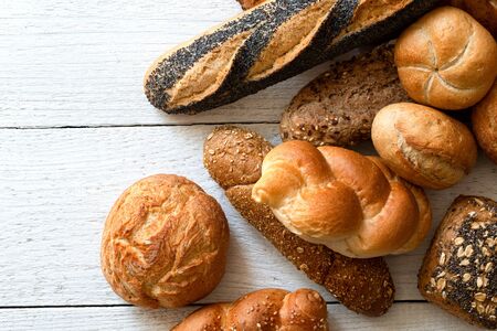 Mixed baguettes and bread rolls on white painted wood. Top view. Space for text.の写真素材