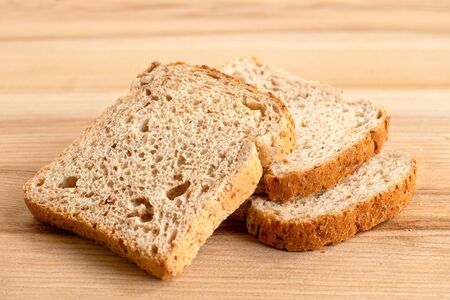 Three slices of whole wheat toast bread isolated on light wood.の写真素材