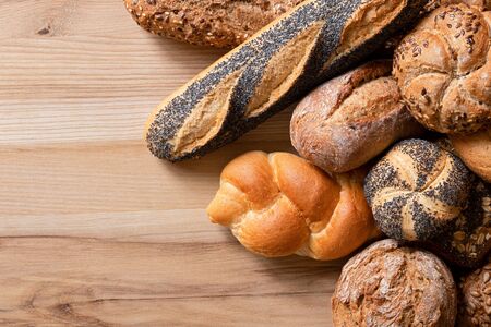 Mixed baguettes and bread rolls on light wood. Top view. Space for text.の写真素材