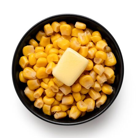 Canned sweet corn with a knob of butter in a black ceramic bowl isolated on white. Top view.の写真素材