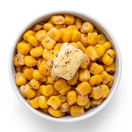 Canned sweet corn with a knob of butter and ground black pepper in a white ceramic bowl isolated on white. Top view.の写真素材