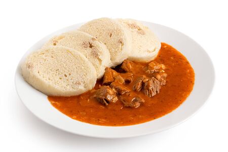 Beef goulash with bread dumplings on white ceramic plate isolated on white.の写真素材